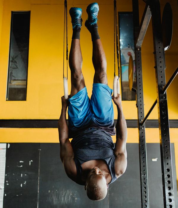 Man performing a controlled strength exercise in a dark gym with cyan highlights.